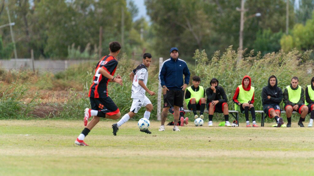 Action-packed amateur soccer match with players in motion and a coach on the sidelines.